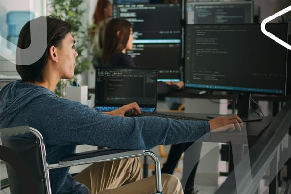 Joven revisa información en computadores dentro de un entorno tecnológico.