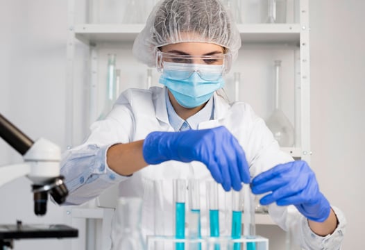 Estudiante de regencia de farmacia realiza práctica de laboratorio con tubos de ensayo y medidas de bioseguridad