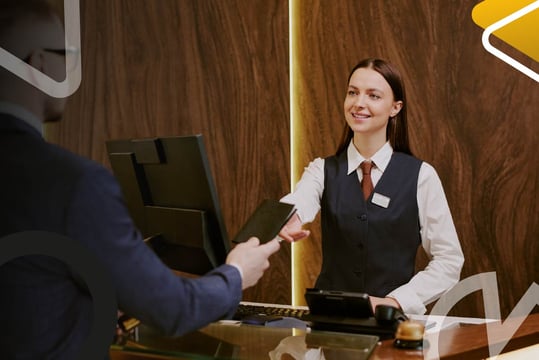 Recepcionista de hotel realiza proceso de atención y registro de huésped en establecimiento de hospedaje